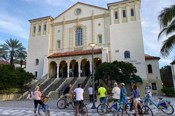 a group of people on a bicycle in front of a building