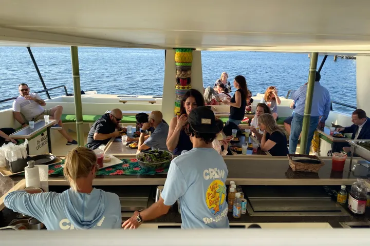 a group of people sitting at a table with food and water