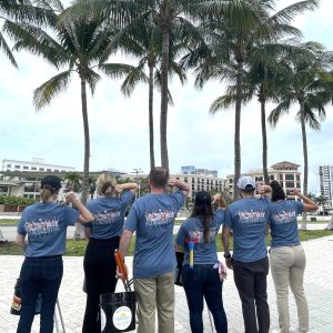 a group of people standing next to a palm tree
