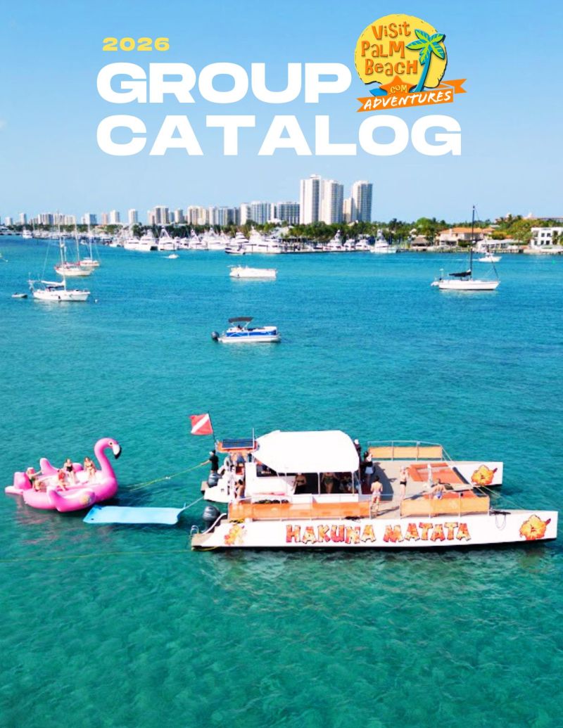 Boat with 'Hakuna Matata' sign in ocean near pink flamingo float, city skyline in background.