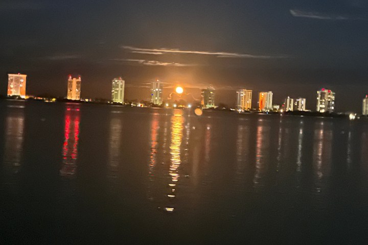 City skyline with illuminated buildings reflecting on water at night.