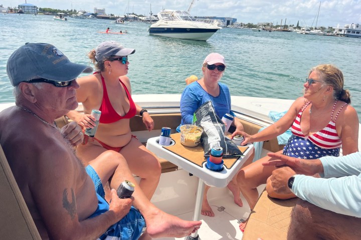 Group relaxing on a boat, enjoying drinks and snacks, with other boats visible on the water.