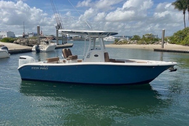 Blue motorboat docked in a marina under a cloudy sky.