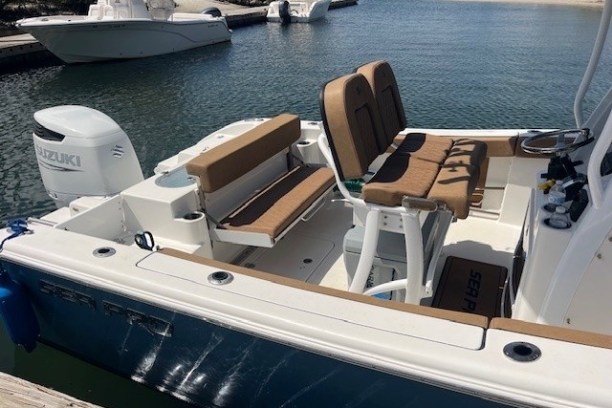 Boat docked with cushioned seating and Suzuki outboard motor.