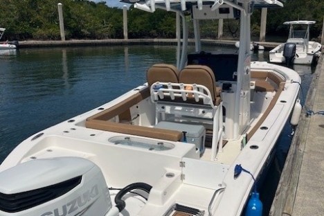 White motorboat docked with fishing rods and Suzuki outboard engine.