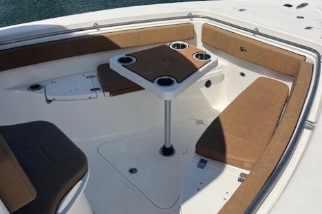 Boat's seating area with a central table and cup holders on a calm water background.